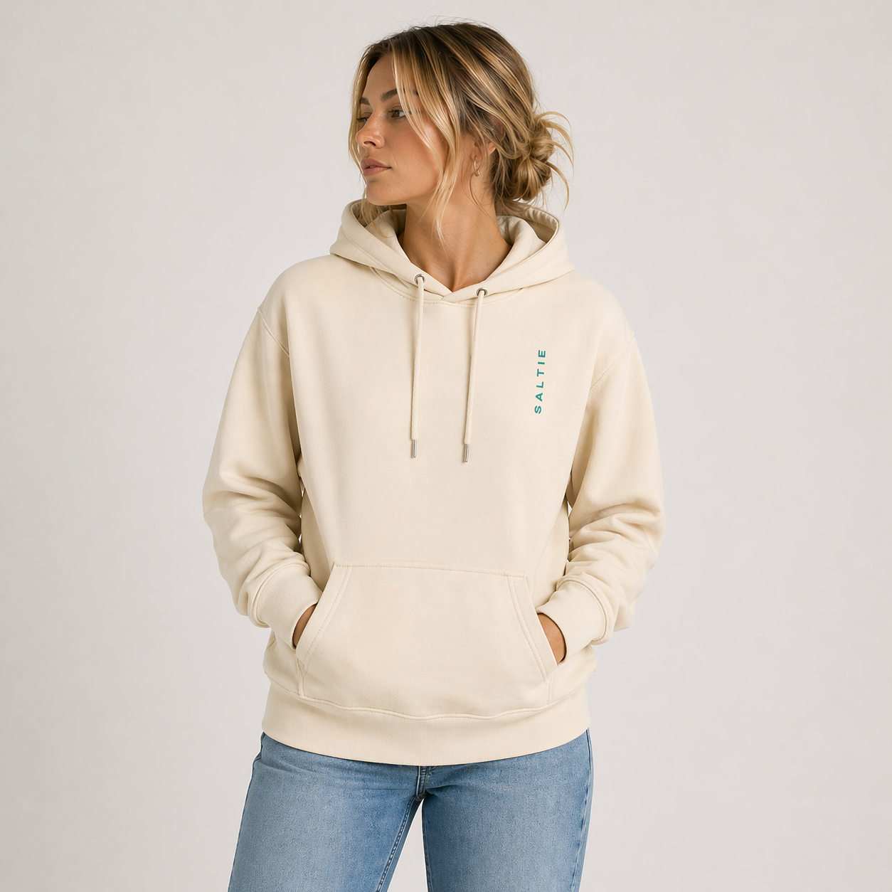 A woman wearing beige hoodie with a small logo