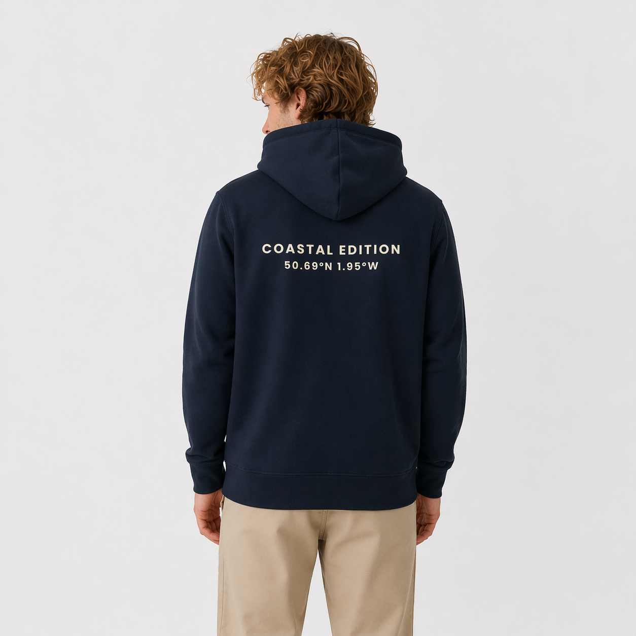 Person wearing a navy hoodie with 'Coastal Edition' text on the back, standing against a light gray background.