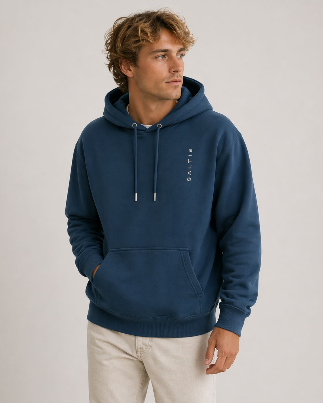 Man wearing a blue hoodie with a brand logo on a light gray background