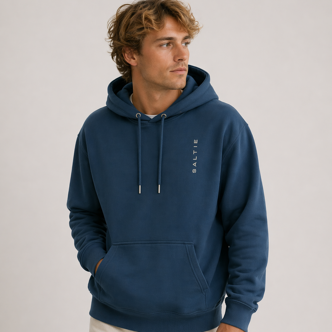 Man wearing a blue hoodie with a brand logo on a light gray background