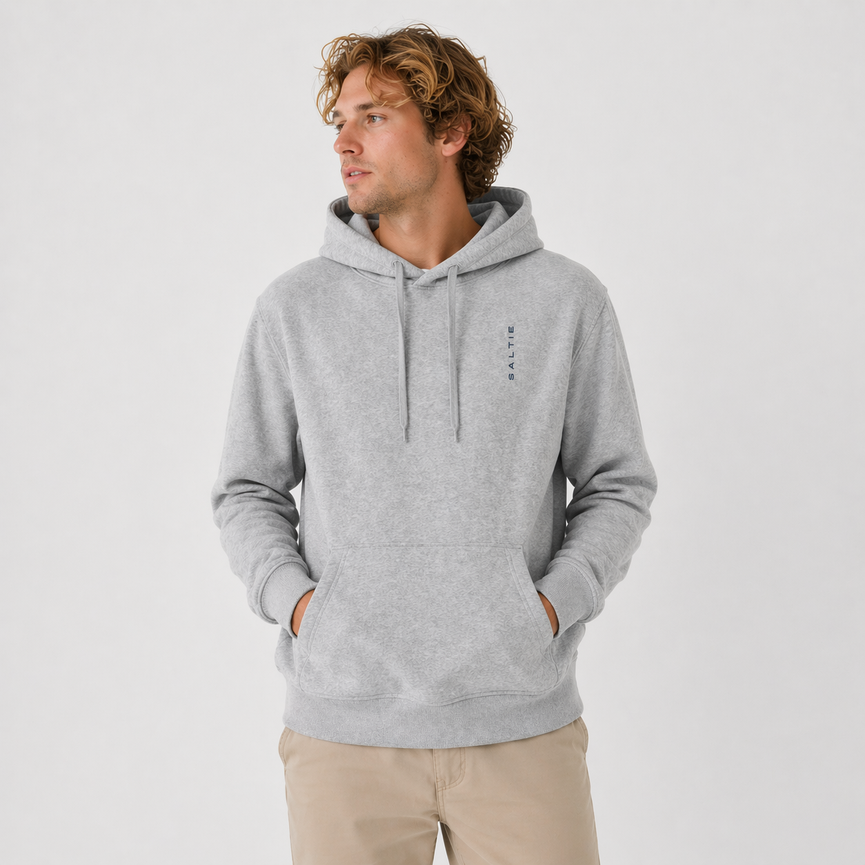 Man wearing a gray hoodie with a small logo on a light gray background