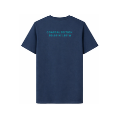 A branded saltie T-shirt against a white background. The main colour a navy blue. The logo is placed on the back of the shirt which reads "coastal edition", in a teal colour.