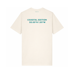 A branded Saltie T-shirt against a white background. The main colour is beige. The image shows the back of the shirt. It reads "coastal edition".