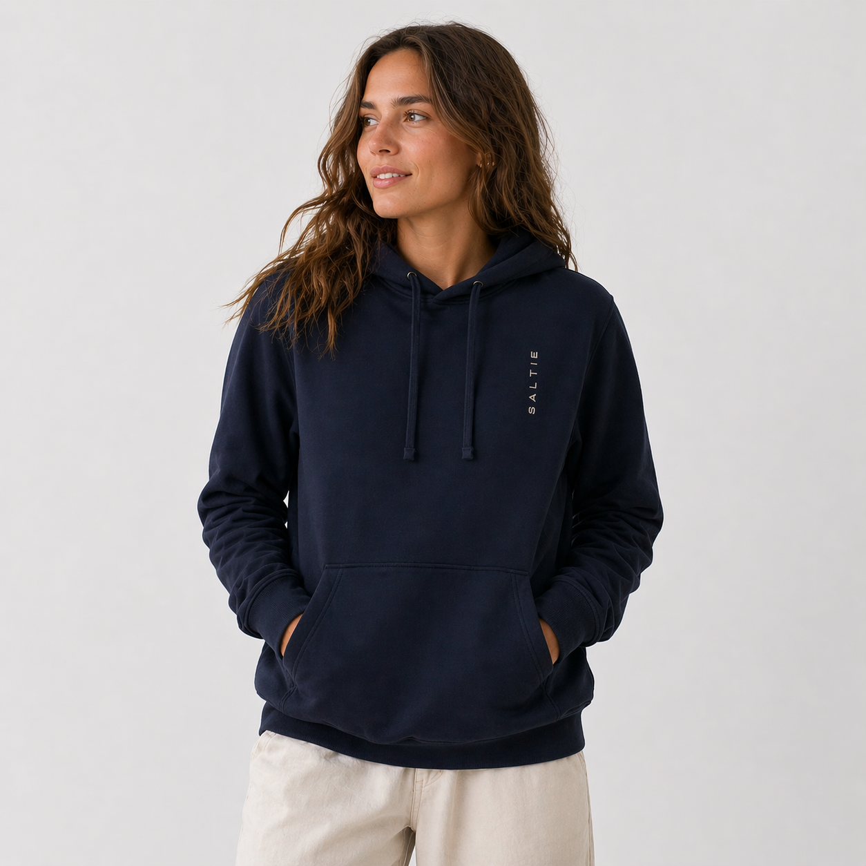 Person wearing a navy hoodie with a logo on a light gray background