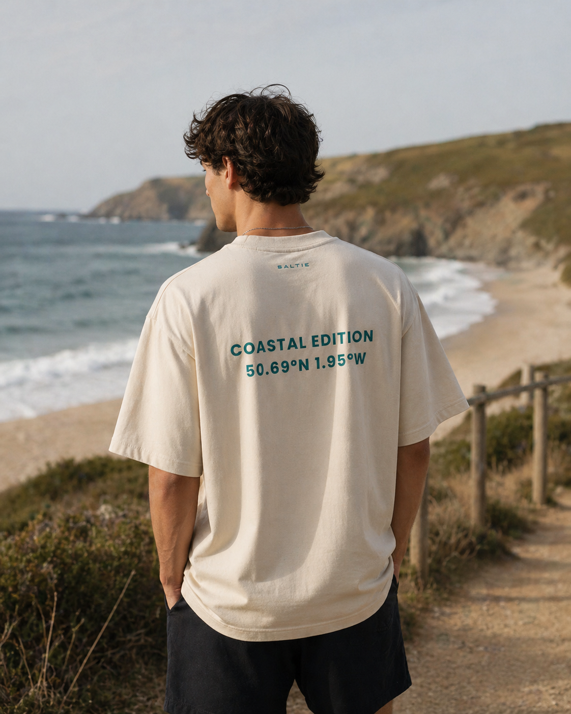 Person wearing a t-shirt with 'Coastal Edition' text standing by the ocean.