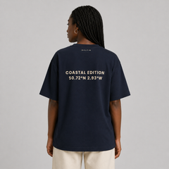 Person wearing a navy blue t-shirt with text on the back, standing against a plain background