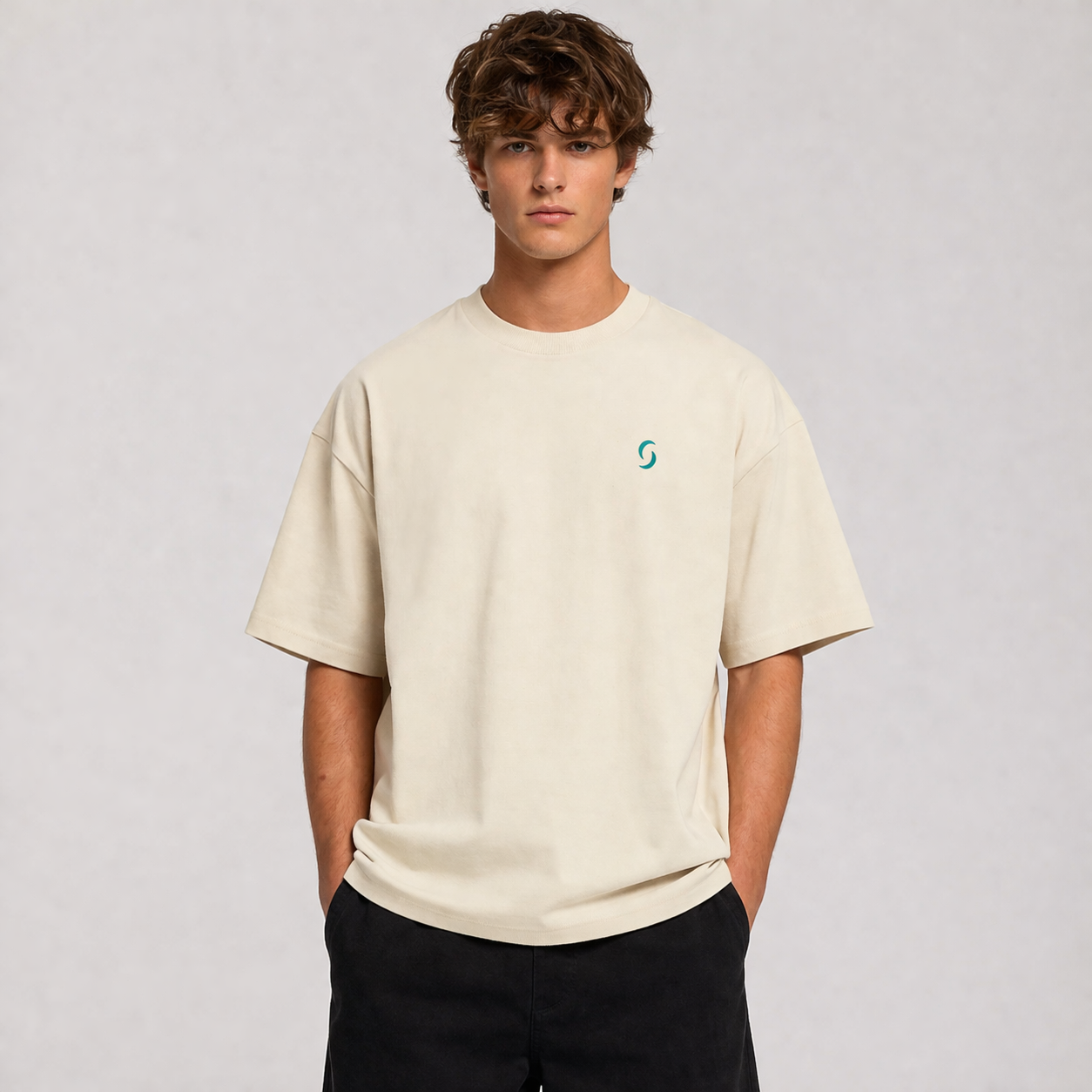 Person wearing a beige t-shirt with a logo on a plain background