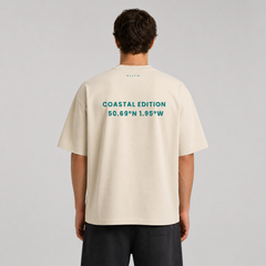 Person wearing a beige t-shirt with text on the back, standing against a gray background