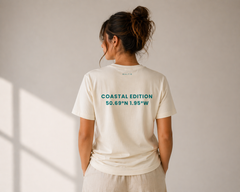 Person wearing a white t-shirt with 'Coastal Edition' text on the back against a plain background